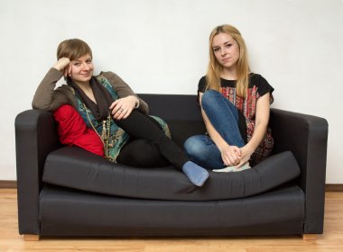 Kadınlar parlak elbiseler siyah kanepede oturan 