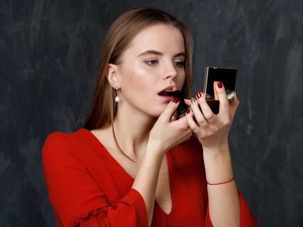 Mujer aplicando lápiz labial mirando al espejo — Foto de Stock