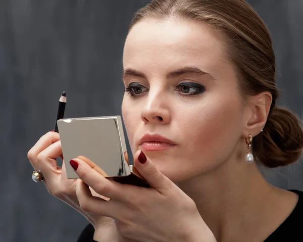 Jovem mulher aplicando maquiagem — Fotografia de Stock