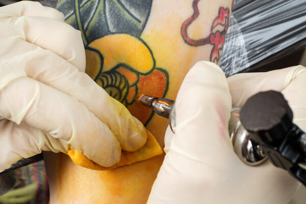 Master making tattoo on the arm