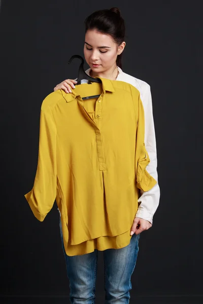 Jolie fille brune tenant une chemise jaune et souriante — Photo