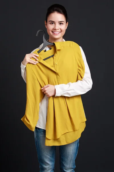 Femme tenant un cintre avec une chemise, l'ajustant et souriant — Photo