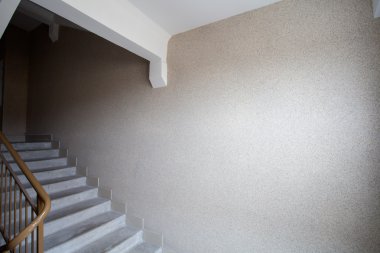  Part of a gray staircase with wooden railing, brown wall