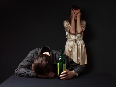 Drunk man is sleeping on the table with the bottle in the hand