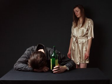  Drunk man is sleeping on the table with the bottle in the hand,