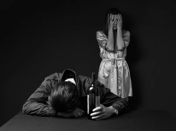 Drunk man is sleeping on the table with the bottle in the hand