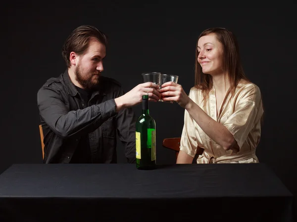 Alcoholism. Man and woman are boozing, bottle on the table, smil — Φωτογραφία Αρχείου
