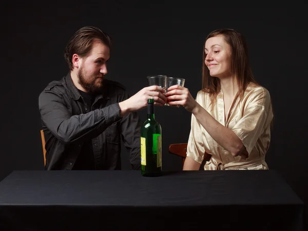 Alcoholism. Man and woman are boozing, bottle on the table, smil — Stock Photo, Image