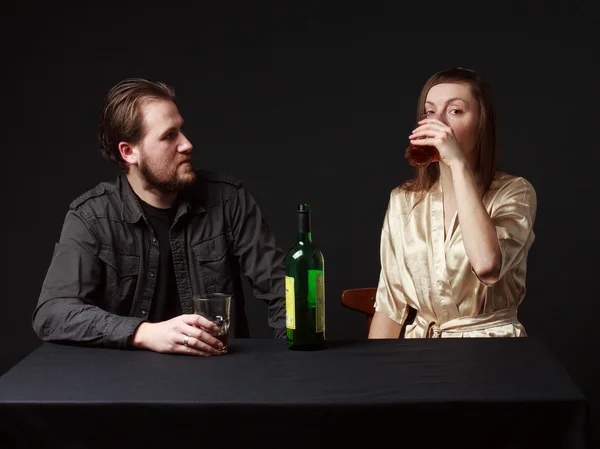 Man and woman are boozing, bottle on the table, keeping glasses. — Stock Photo, Image