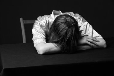 Despair. Woman is lying on the table, head on the hands clipart