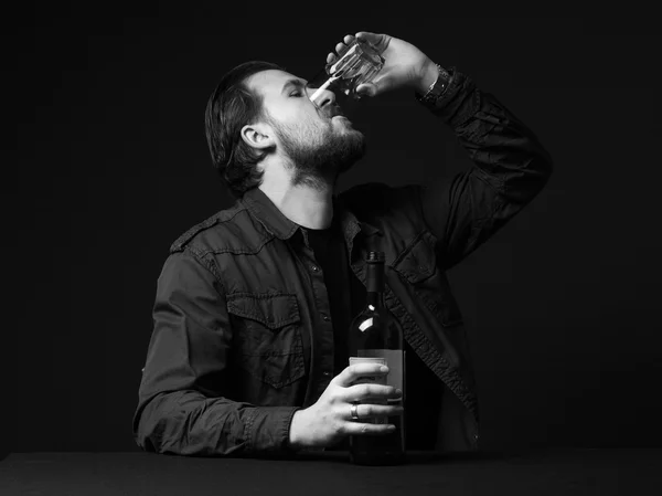 A fiatalember alkoholfogyasztás a borospohár, üveg, a t — Stock Fotó