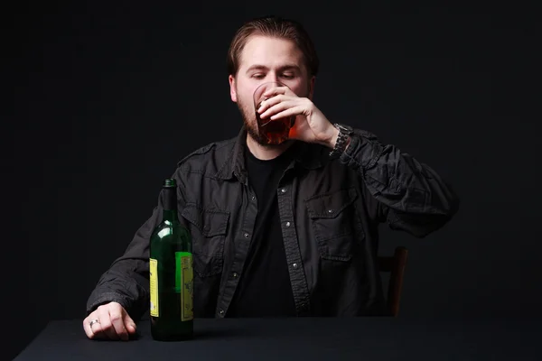 Joven está bebiendo alcohol de una copa de vino, botella en la t —  Fotos de Stock