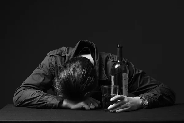 Alcoholic durmiendo en la mesa con la botella en la mano — Foto de Stock