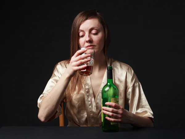 Alcoolismo. Jovem está a guardar uma garrafa e um copo de vinho. — Fotografia de Stock
