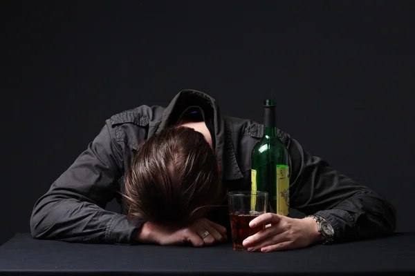 Alcoholic sleeping on the table with the bottle in the hand Stock Photo