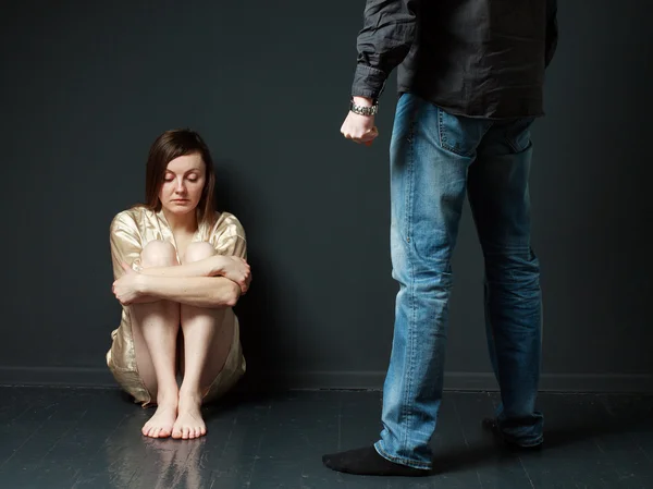 Sad woman is sitting on the floor, standing man's figure  threat — Stock Photo, Image