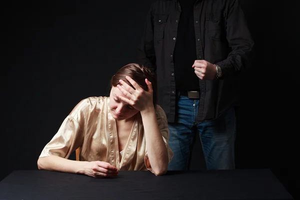 Sad woman is sitting , keeping hand on the forehead, man's figur — Stock Photo, Image