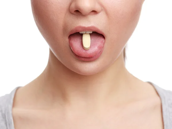 Jovem a tomar um comprimido. O rosto da menina de perto com uma pílula na língua — Fotografia de Stock