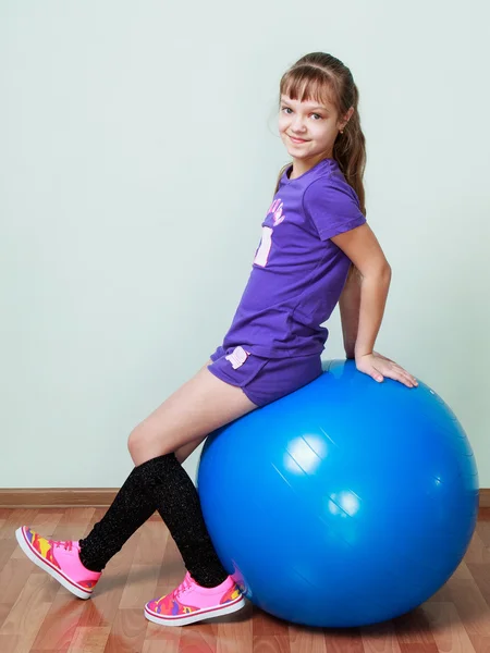 Little girl  is sitting on a blue fit ball at the gym — Stockfoto