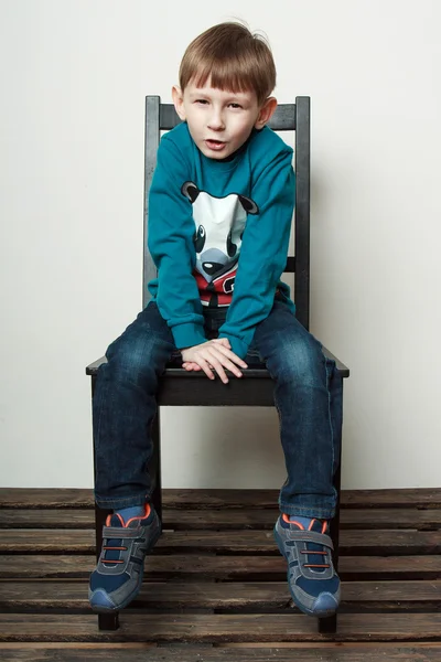 Little funny  boy is sitting on the chair, piddling, fooling — Stock Fotó