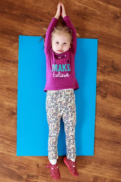 Niña está haciendo ejercicio de estiramiento en una estera — Foto de Stock