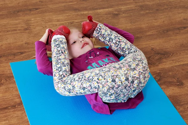 Little girl is doing stretching workout on a mat. — Stock Photo, Image