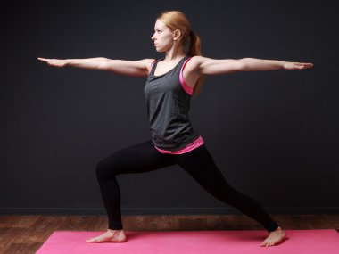  Young blonde woman staying in warrior pose clipart