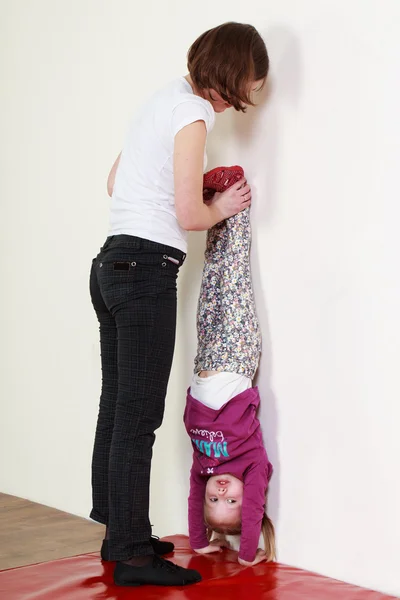 Niña y un entrenador están haciendo una parada de manos — Foto de Stock