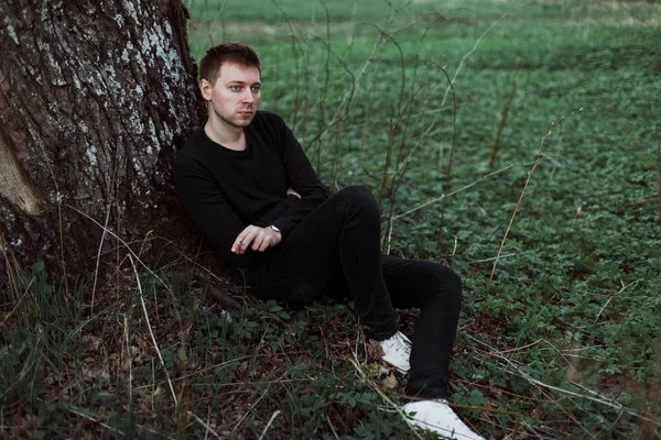 Triste hombre se sienta debajo de un árbol y fuma —  Fotos de Stock