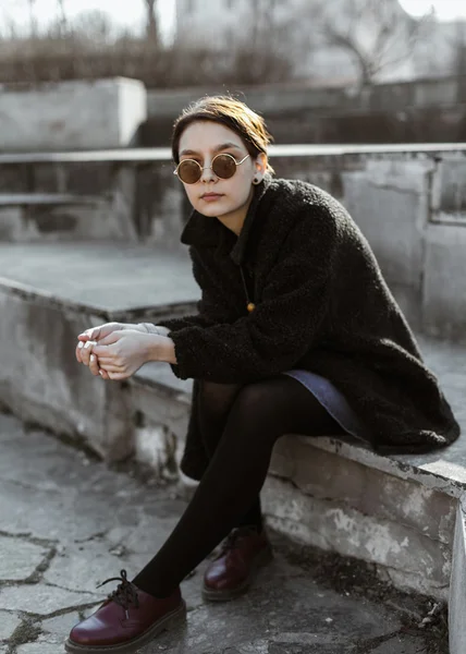 Девушка в солнечных очках сидит на улице — стоковое фото