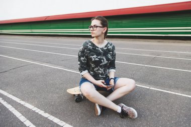 Hippi kız longboard üzerinde oturan 