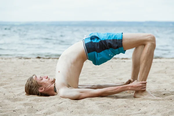 Hombre barbudo practica yoga en la playa — Foto de Stock