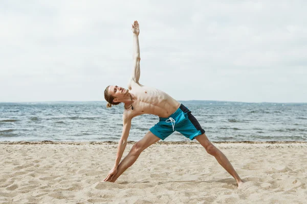 Hombre adulto haciendo yoga en la playa — Foto de Stock