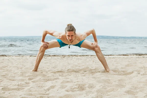 Hombre guapo haciendo yoga en la playa — Foto de Stock