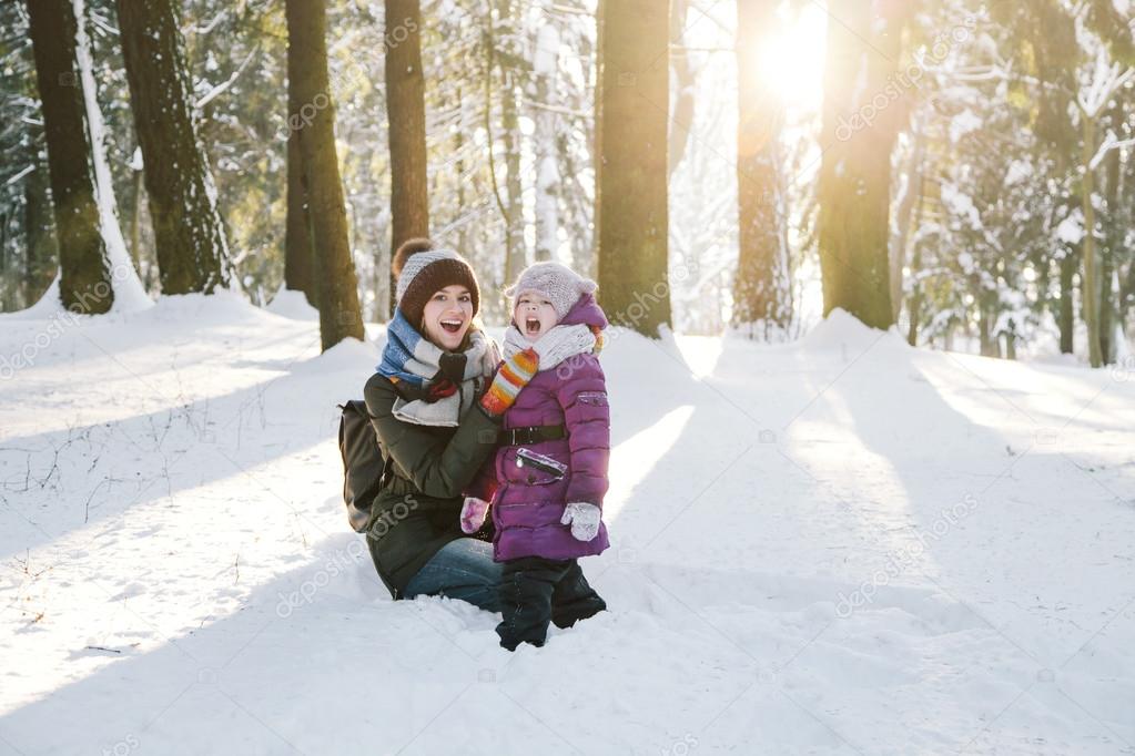 Happy mother and daughter in winter forest