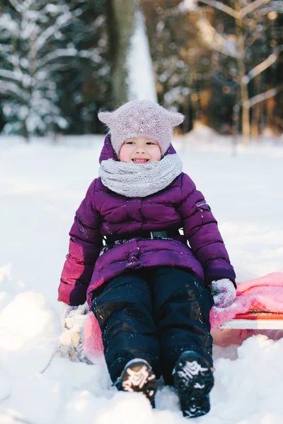 Meisje zitten op slee in de winter forest — Stockfoto