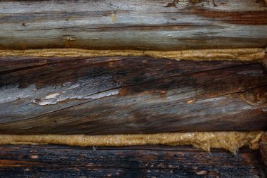 Aged, cracked and discolored logs of the building close up.