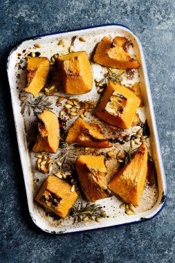 Bir tepsi rustik altın fırınlanmış balkabağı.