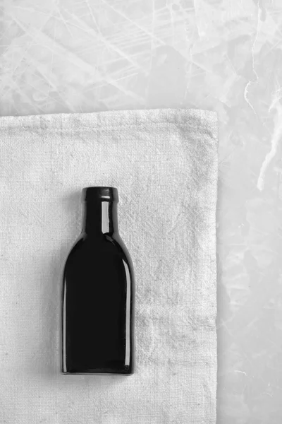 Weinig zwarte fles legt op een grijze doek — Stockfoto