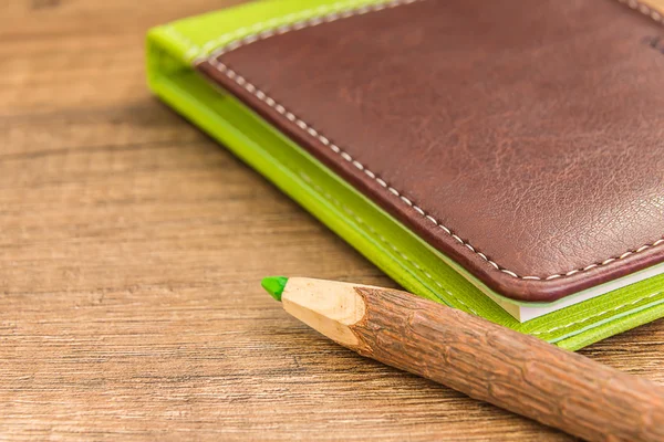 Lápiz de madera verde y marrón libro de trabajo de cuero verde —  Fotos de Stock