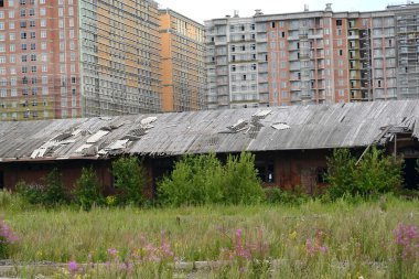 Old railway workshops against a housing estate under construction. St. Petersburg clipart