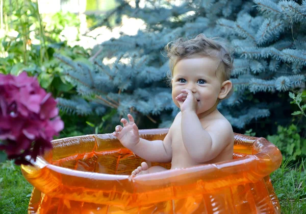 La petite coquine est assise dans la piscine gonflable d'un jardin. Portrait — Photo