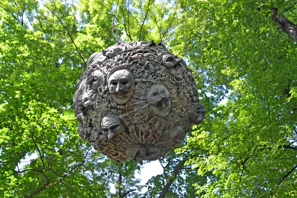 ST. PETERSBURG, RUSIA - 16 DE JULIO DE 2014: La esfera decorativa con máscaras teatrales cuelga del fondo del follaje. Jardín Izmaylovsky —  Fotos de Stock