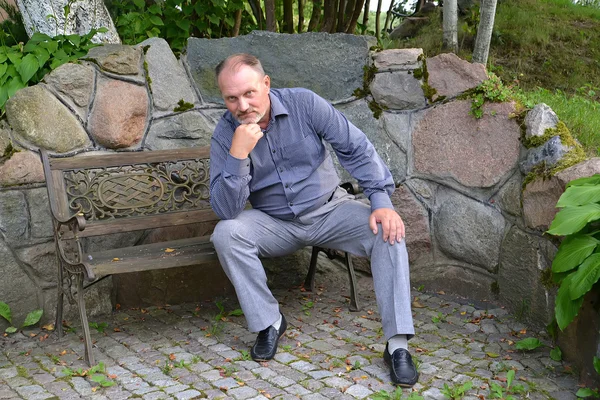 L'homme des années moyennes est assis sur un banc décoratif — Photo