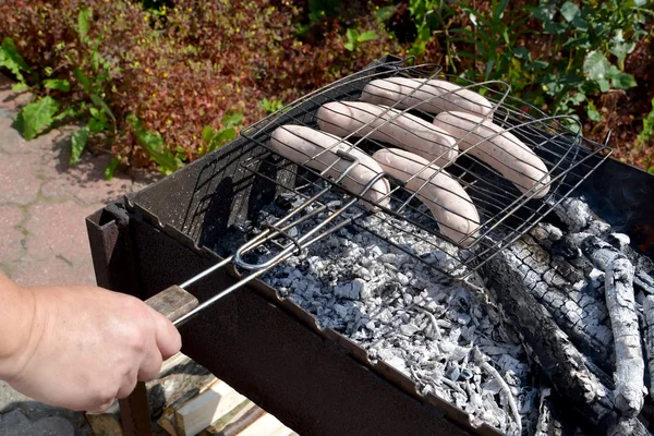 The man fries sausages on a brazier — Stock Photo, Image