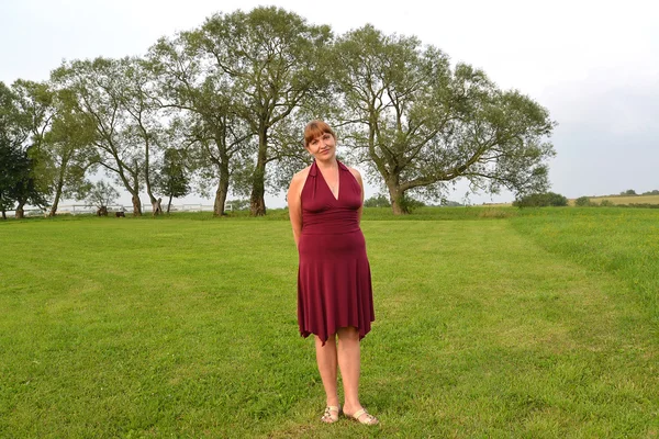 La femme mûre coûte sur la prairie, ayant pris les mains pour le dos — Photo