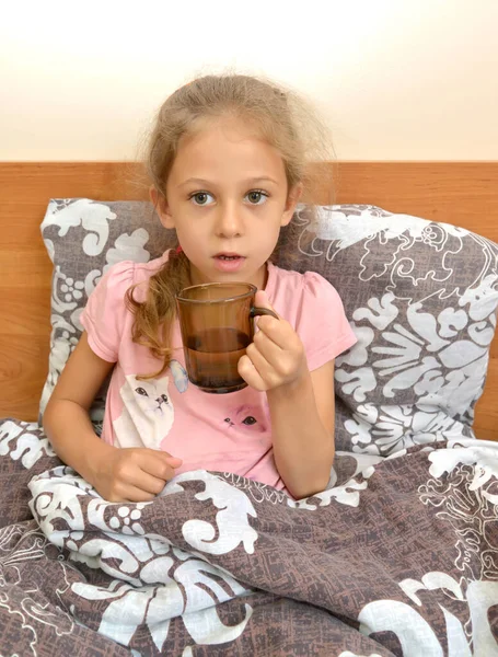 Beş Yaşında Bir Kız Elinde Bir Kupa Suyla Yatakta Oturuyor — Stok fotoğraf