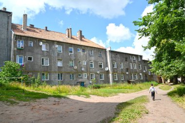 Küçük bir çocuk eski binaların yanından geçen bir patika boyunca yürüyor. Sovetsk, Kaliningrad bölgesi