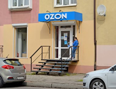 KALININGRAD, RUSSIA - MAYIS 04, 2021: Bir çevrimiçi mağaza çalışanı OZON ön kapının yanında duruyor