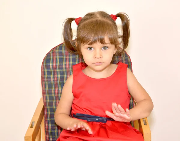Portrait of the little girl sitting on a children's chair on a l — Stock Photo, Image